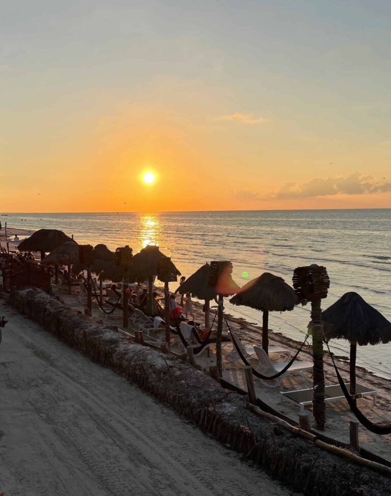 beach shoreline featuring several palapas during sunset in Isla Holbox, Mexico