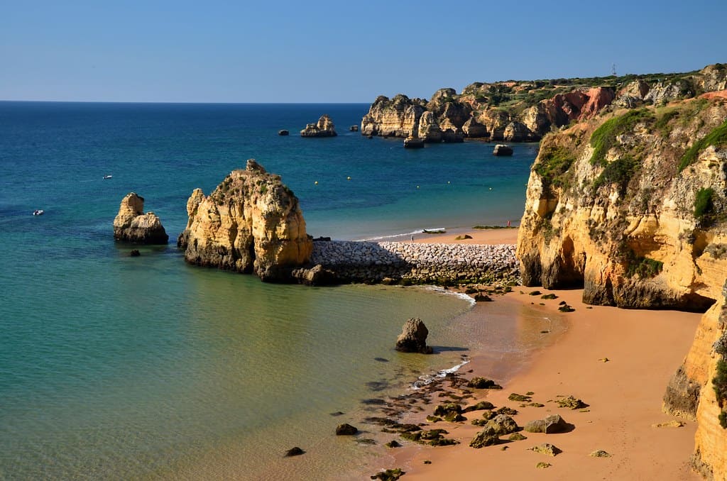 secluded empty beach with large cliffs by the shoreline in Lagos, Portugal
