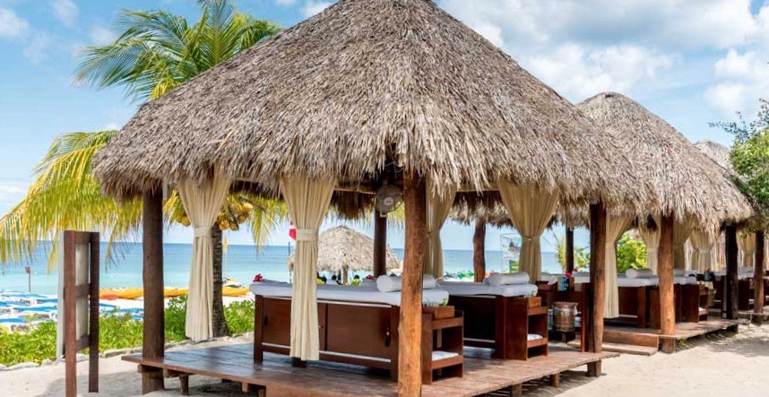 palapas on the beach with palm trees in the background and the Caribbean sea at mr sanchos beach club in cozumel mexico 