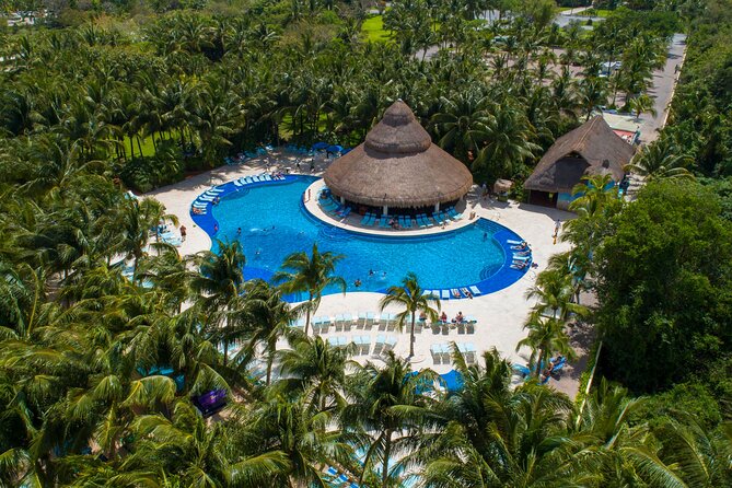 aerial view of paradise beach cozumel featuring a large pool and serval pool lounge chairs and bar
