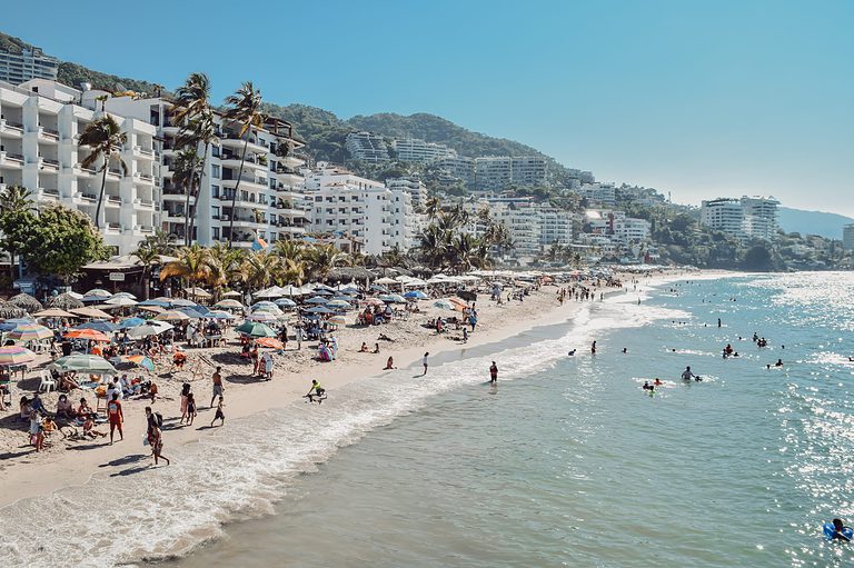 crowded beach shoreline full of high-rise buildings behind it in Puerto Vallarta Mexico, one of the safest cities in Mexico/ things to do in Puerto Vallarta