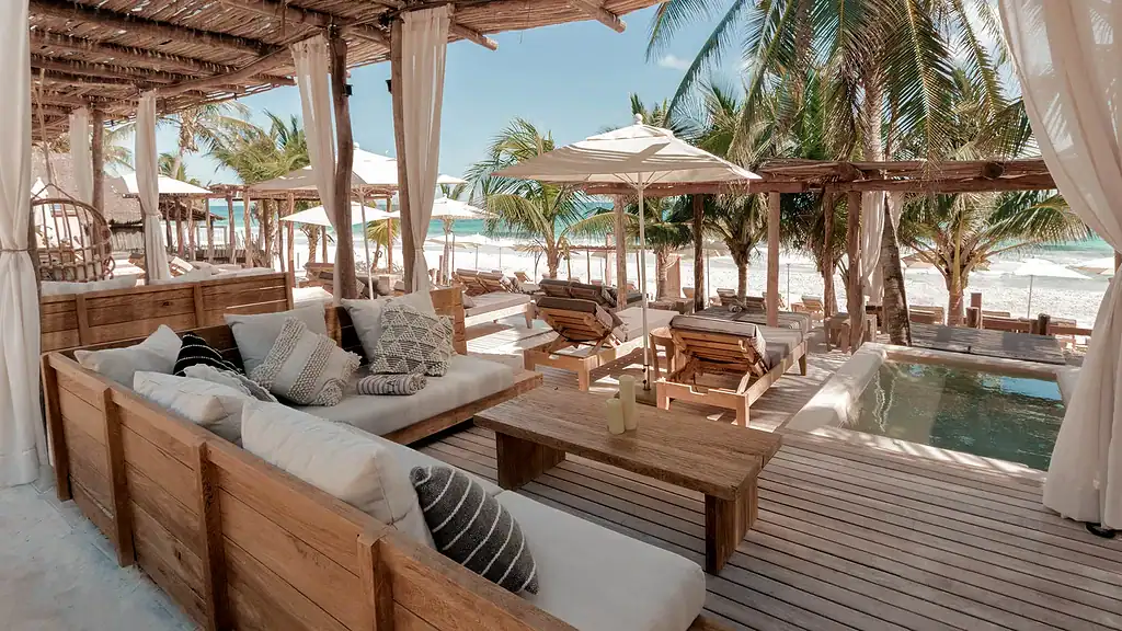 many beach lounge chairs on a private beach at tantra beach club featuring umbrellas and stunning views of the sea