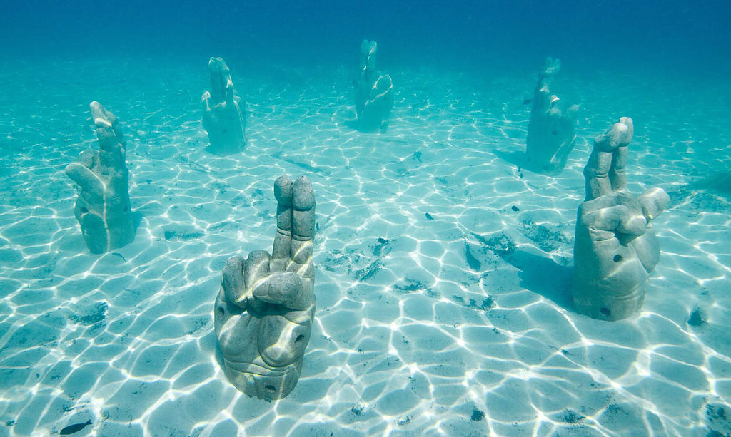 sculptures of fingers crossed underwater at the famous underwater museum in Cancun's waters in Mexico