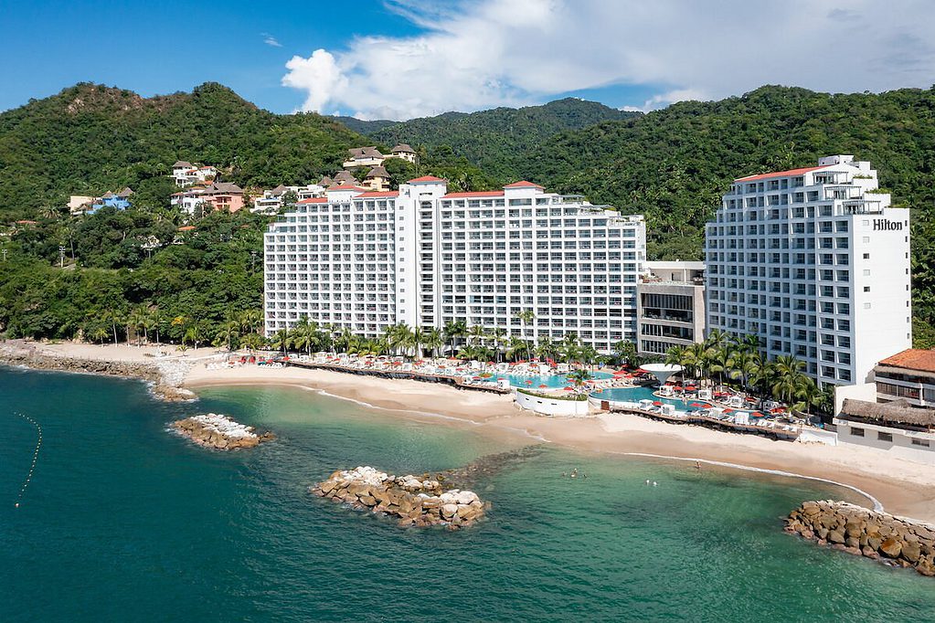 aerial view of the beautiful Hilton between dense green mountain tops and a private beach
