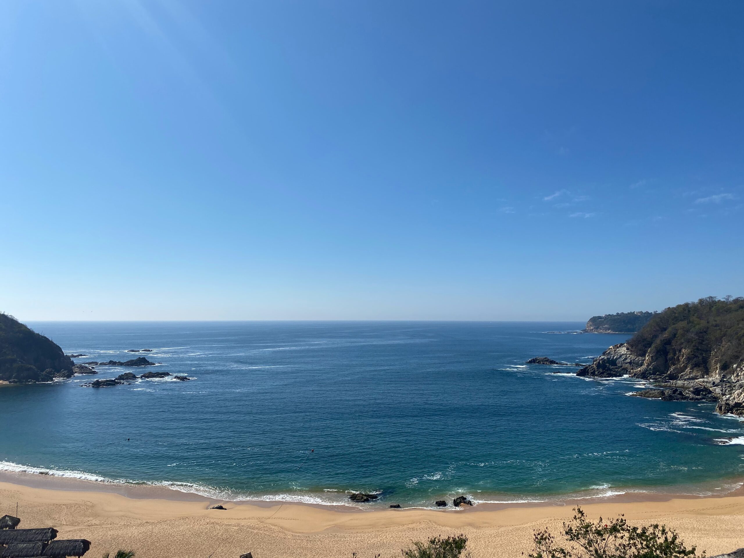 large beach shoreline with clear blue skies in Huatulco, Mexico / best things to do in Huatulco