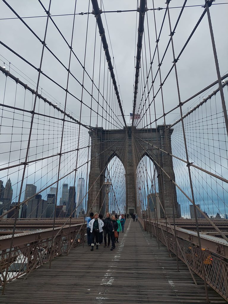view looking upwards of tourists walking along the famous Brooklyn Bridge in New York City