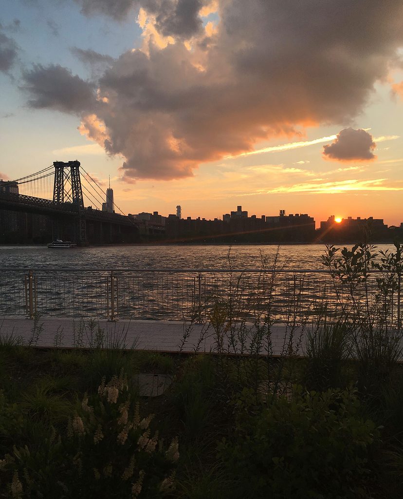 sunset with the New York City skyline views from Domino Park boardwalk in Williamsburg, Brooklyn