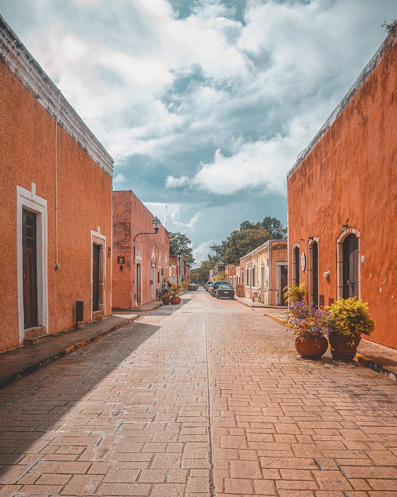 the bright beautiful streets of Valladolid, Mexico showing small buildings with various colour hues and clear skies