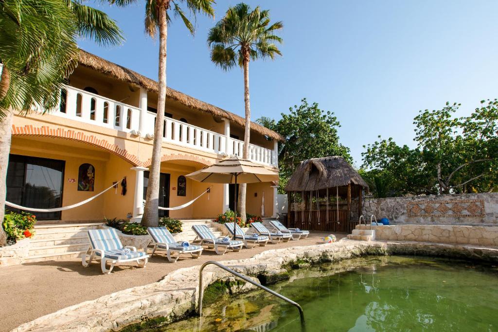 sunbathe area featuring several beach lounge chairs and palm trees at the Chez Waffle Hotel in Puerto Aventuras in Mexico 
