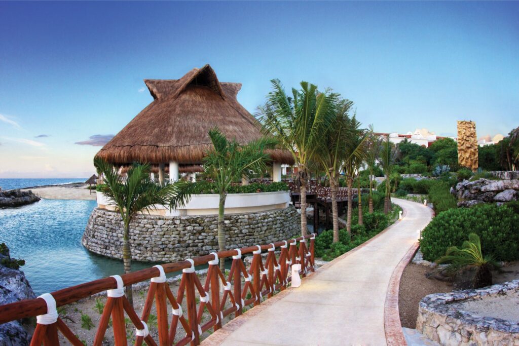walkway full of greenery and a large palapa bar along the coastline at the Hard Rock Hotel Riviera Maya in Mexico