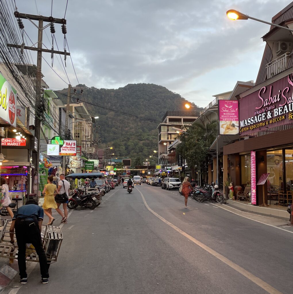 Tourist walking on a street in the evening time in Kata Beach as the sun is setting in