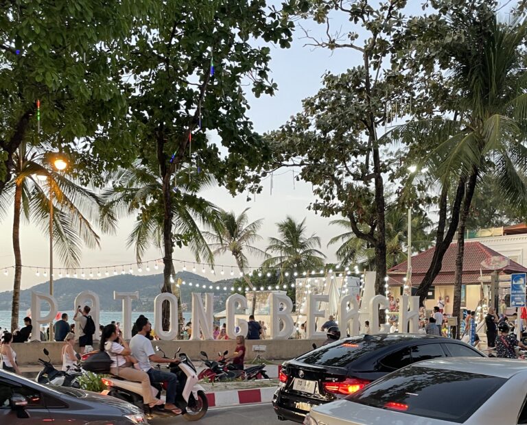 alternative white Patong Beach sign standing in front of Patong beach at sunset, surrounded by palm trees in Patong, Phuket / how to get from Phuket airport to Patong beach