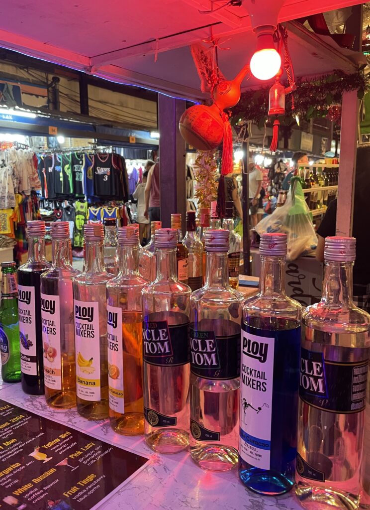 plenty liquor bottles lined up at a bar under a red light in Patong Beach