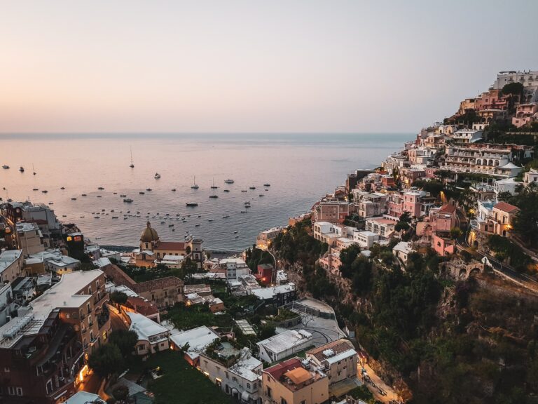 views of the hills of Positano with several boats anchored at the shores during sunset in Positano, Italy / is Positano expensive to visit