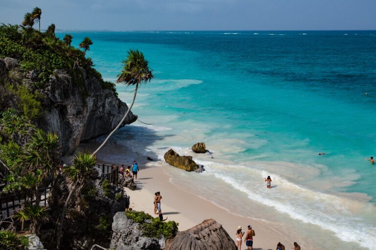 views of the stunning Caribbean Sea surrounded by cliffs and palm trees in Tulum, Mexico