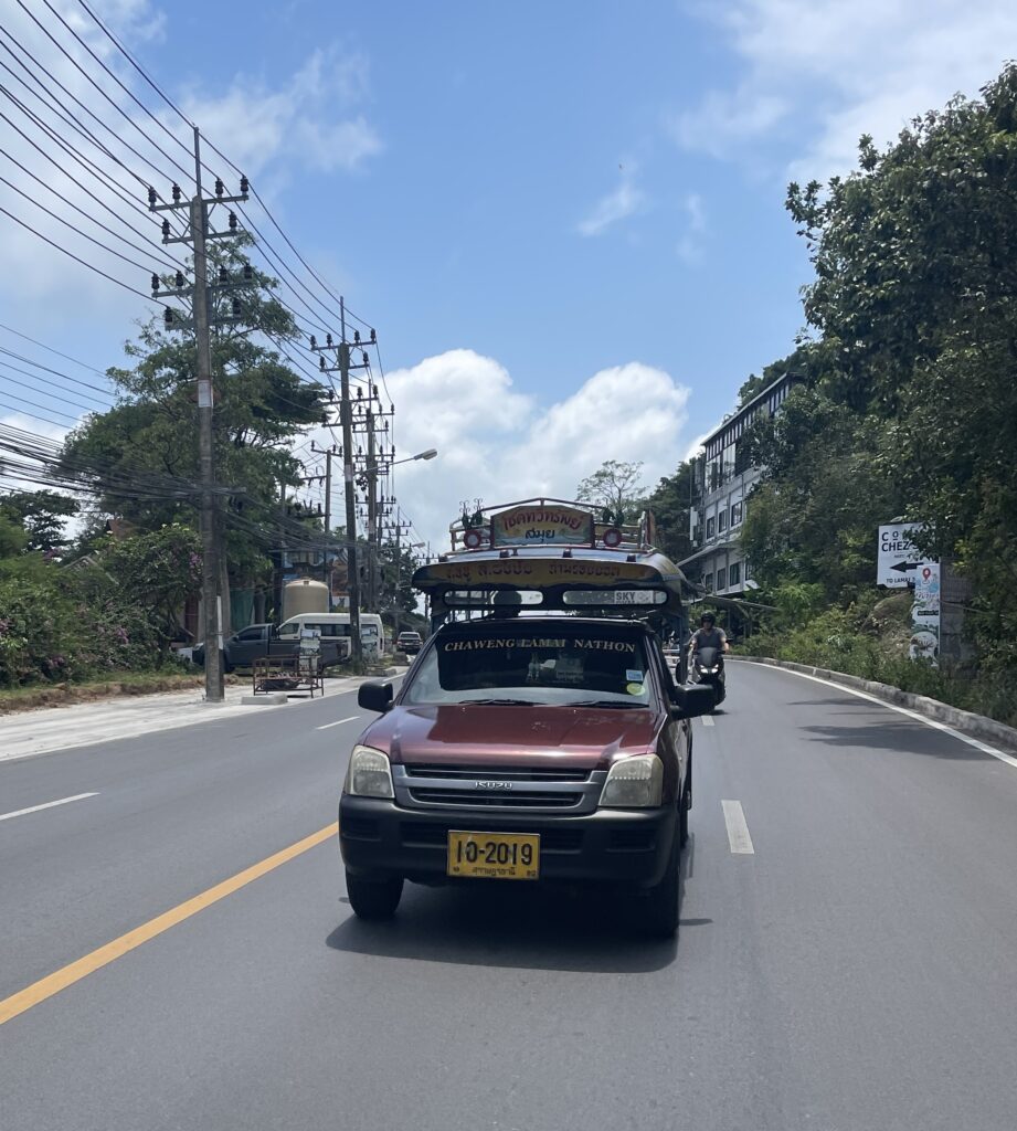 songtaew, a pubic transportation taxi van driving throughout the island on a sunny clear day