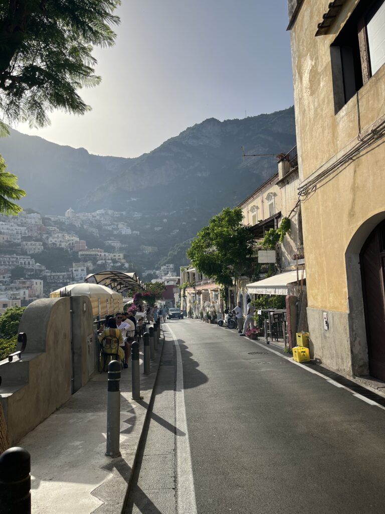 one of the most picturesque streets in all of Positano, showcasing mountains in the distance on a sunny day