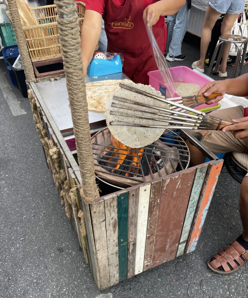Thai man cooking a rice thin cake dessert at the Old Phuket Town Sunday Market