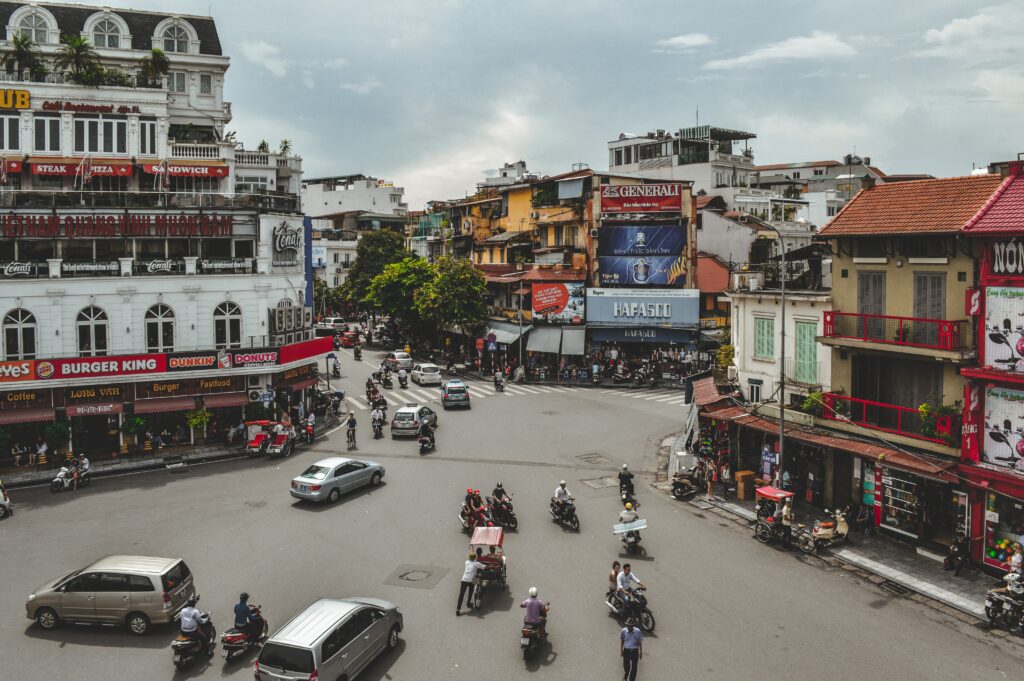 several locals driving by on scooters on a busy intersection in Hanoi, Vietnam 