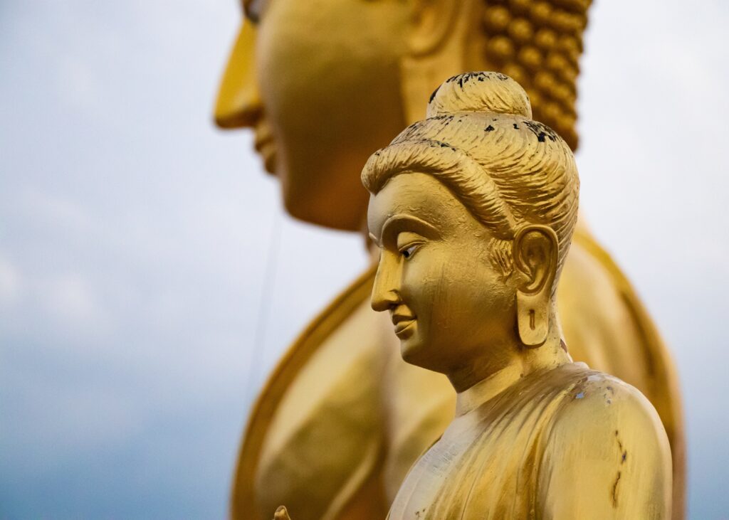 two golden buddha statues at the top of Tiger Temple in Krabi, Thailand