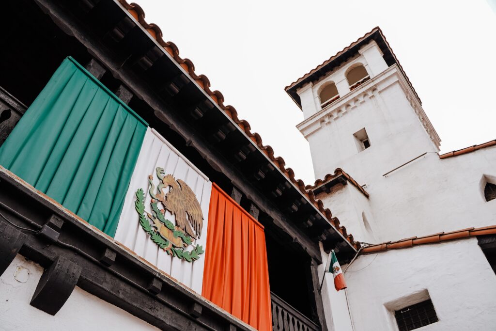 two buildings in the city centre of Ensenada, Mexico / one with the Mexican flag decorated on it 