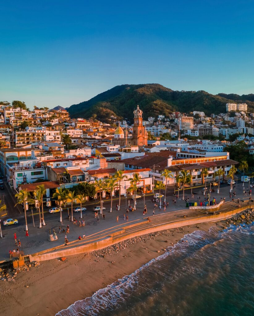 aerial views of many buildings, mountains in the distance and the main boardwalk along the Pacific Ocean in Puerto Vallarta