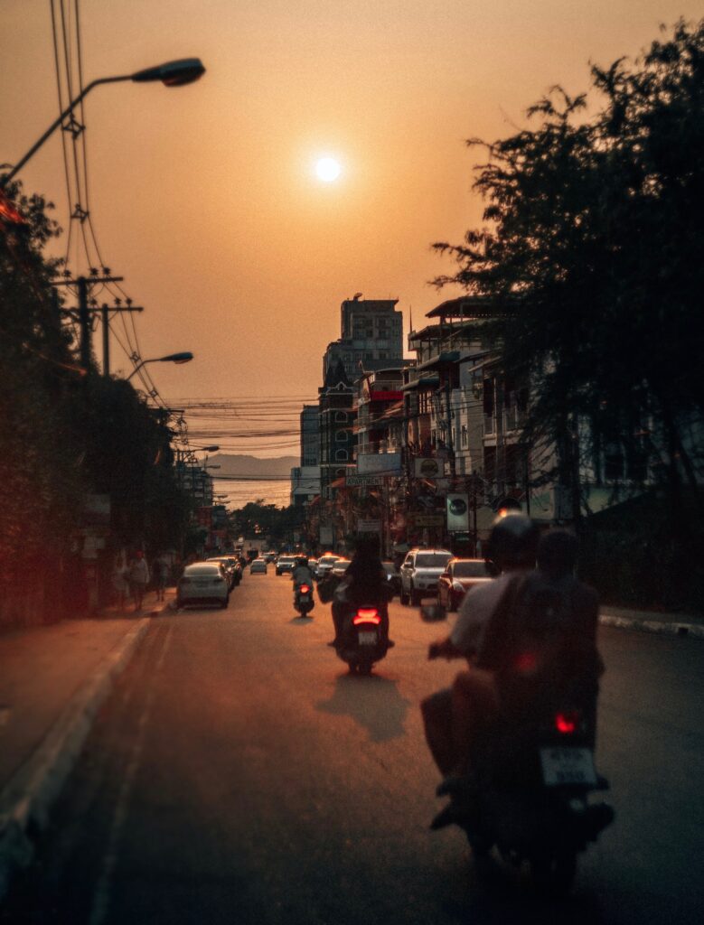 several scooters riding around at sunset in Pattaya City, Thailand