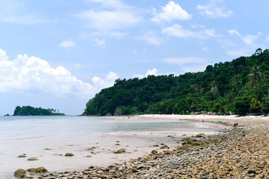 stunning calm beach shoreline full of dense green jungle int he background in Koh Chang