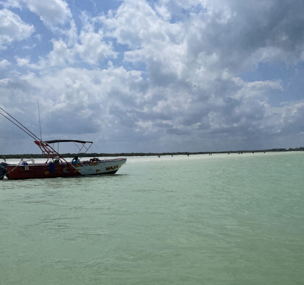 a small boat docked along the turquoise waters near Bird Island in Isla Holbox