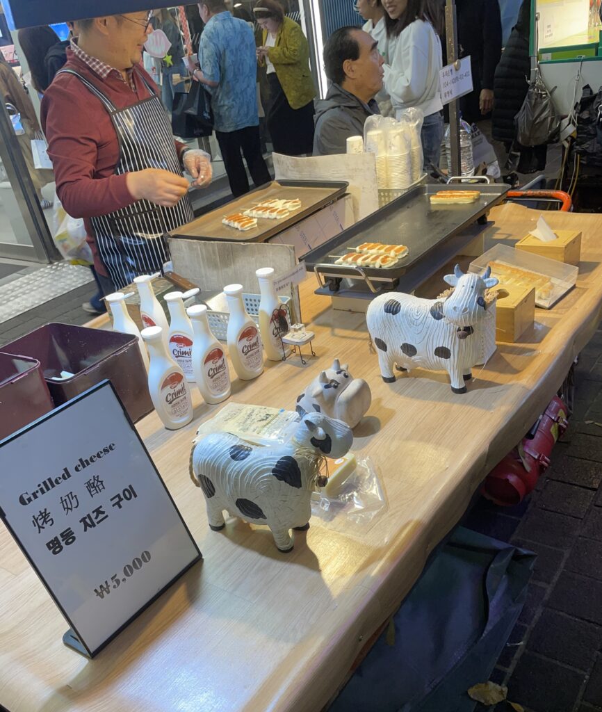food stall selling his perfectly grilled cheese skewers at the night market in Myeongdong 