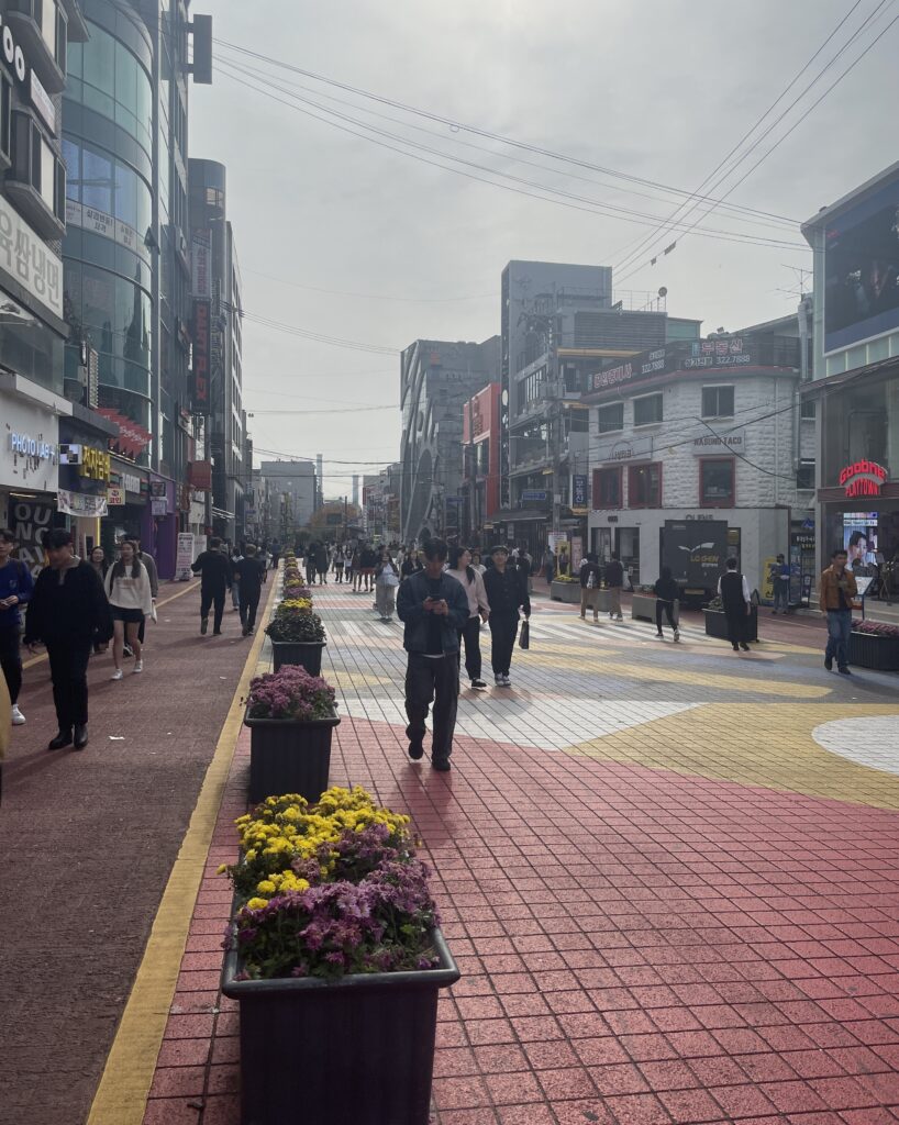 locals and tourists walking along the popular Hongdae Shopping Street on a sunny day in Seoul