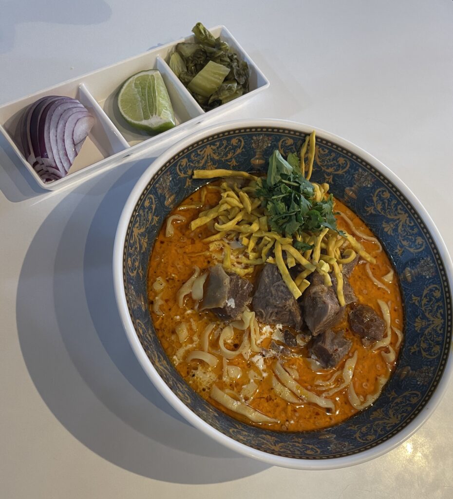 red curry Khao Soi served with three side toppings at Khao Soi Doi Nang