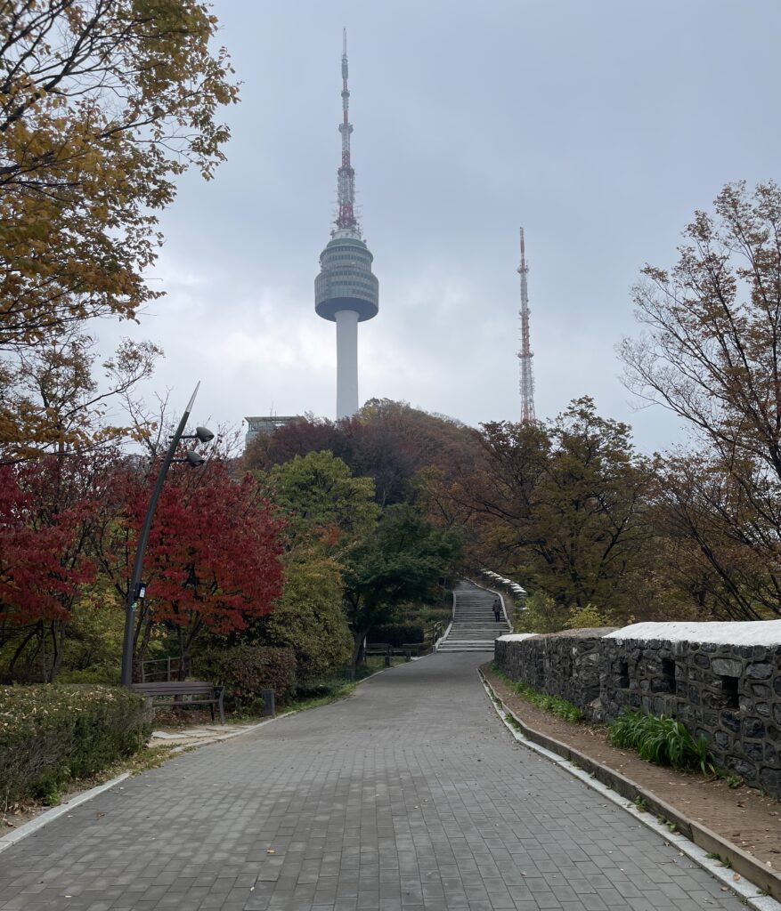 trail uphill the mountain towards N Seoul Tower with several bright coloured trees in the Fall