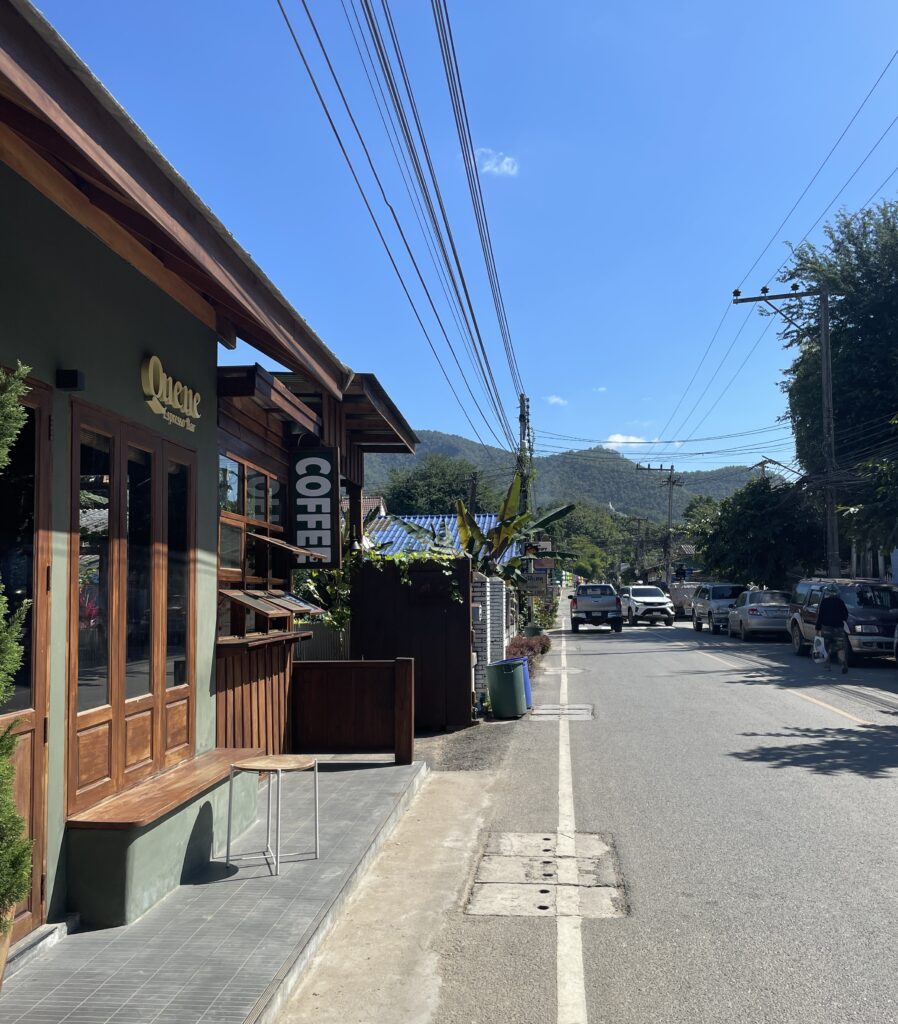 street with mountains in the distance and a street cafe on the side of the road 
