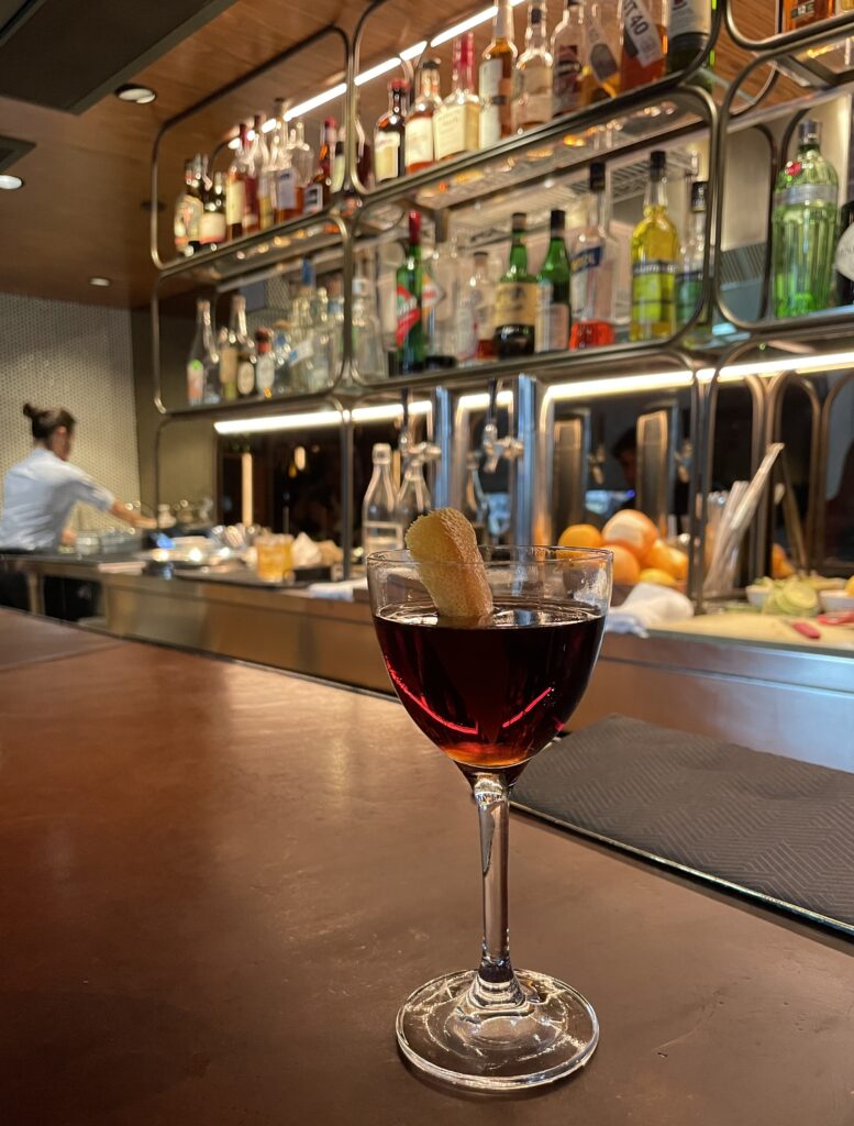 a cocktail with beautiful dim lit bar in the background at Aloette in Toronto