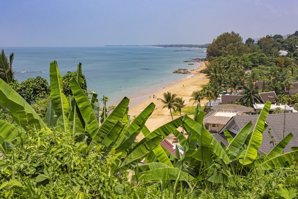 a stunning beach shoreline with a few tourist walking on a sunny day in Khao Lak 