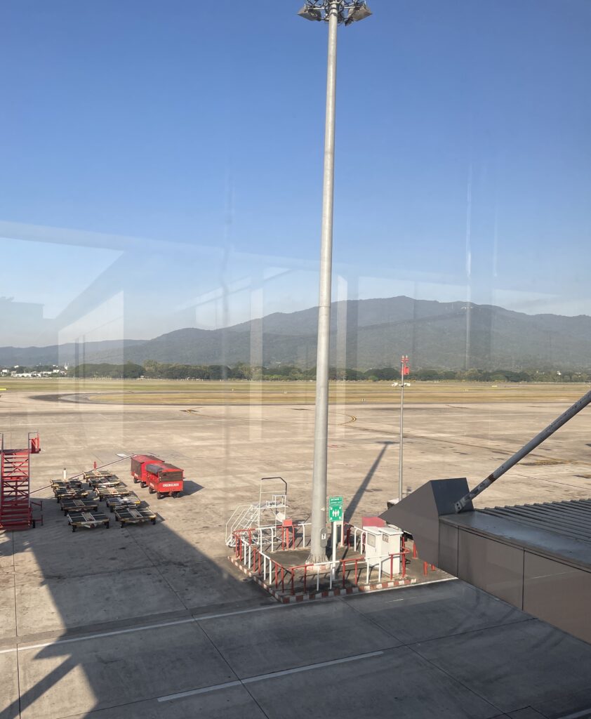 clear grounds at Chiang Mai airport with mountains in the distance in the morning 