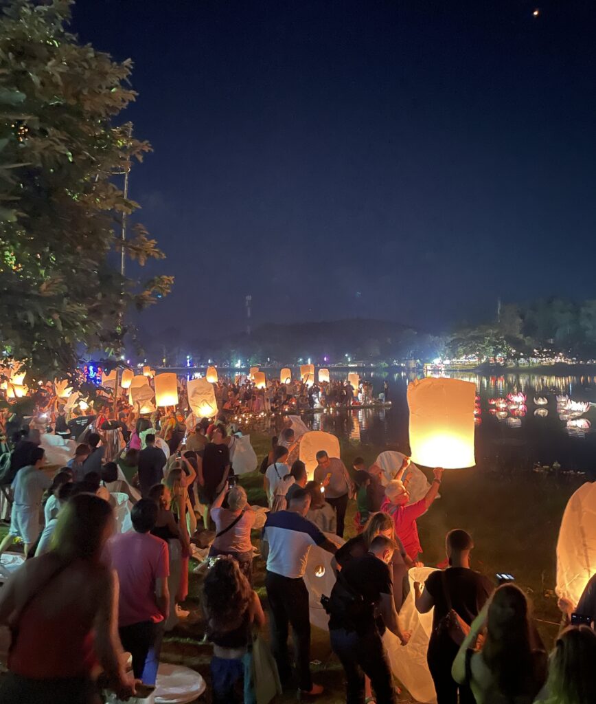 several people beginning to release their lanterns into the dark sky during Yi Peng Festival in Chiang Mai