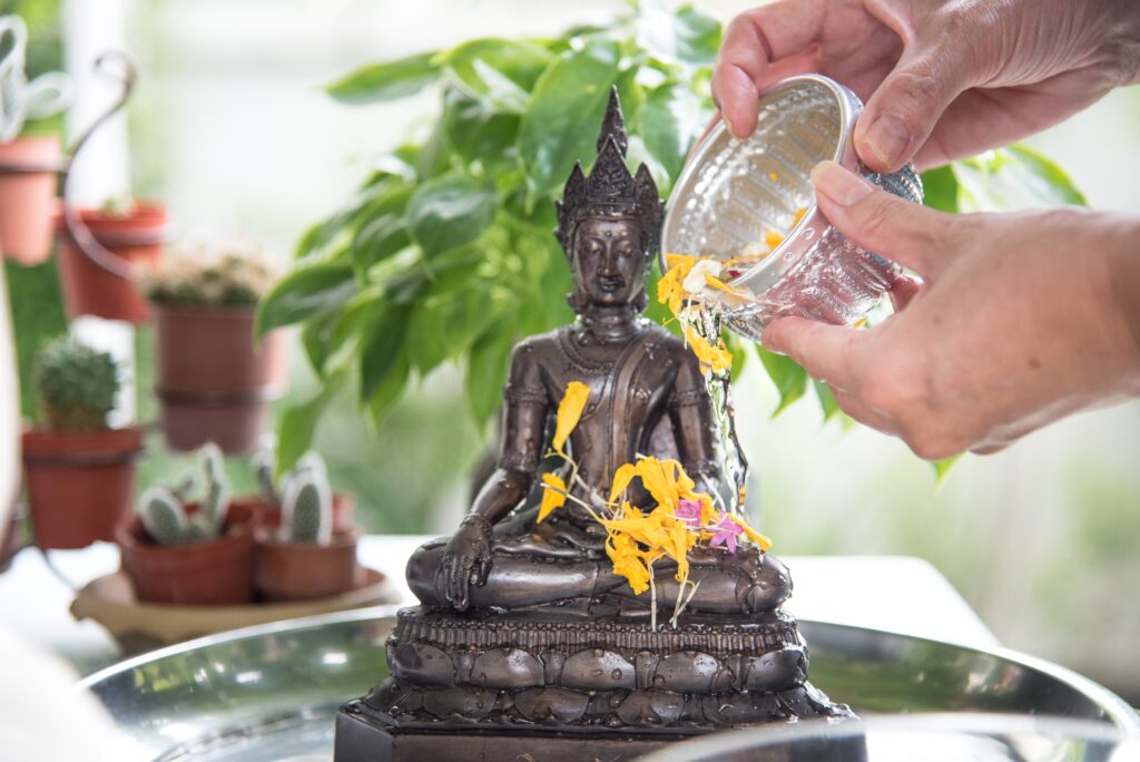 small Buddha statue having water poured on it 