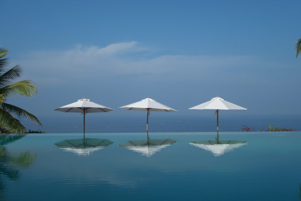 three white umbrellas along an infinity pool on a clear day in Koh Lanta, Thailand