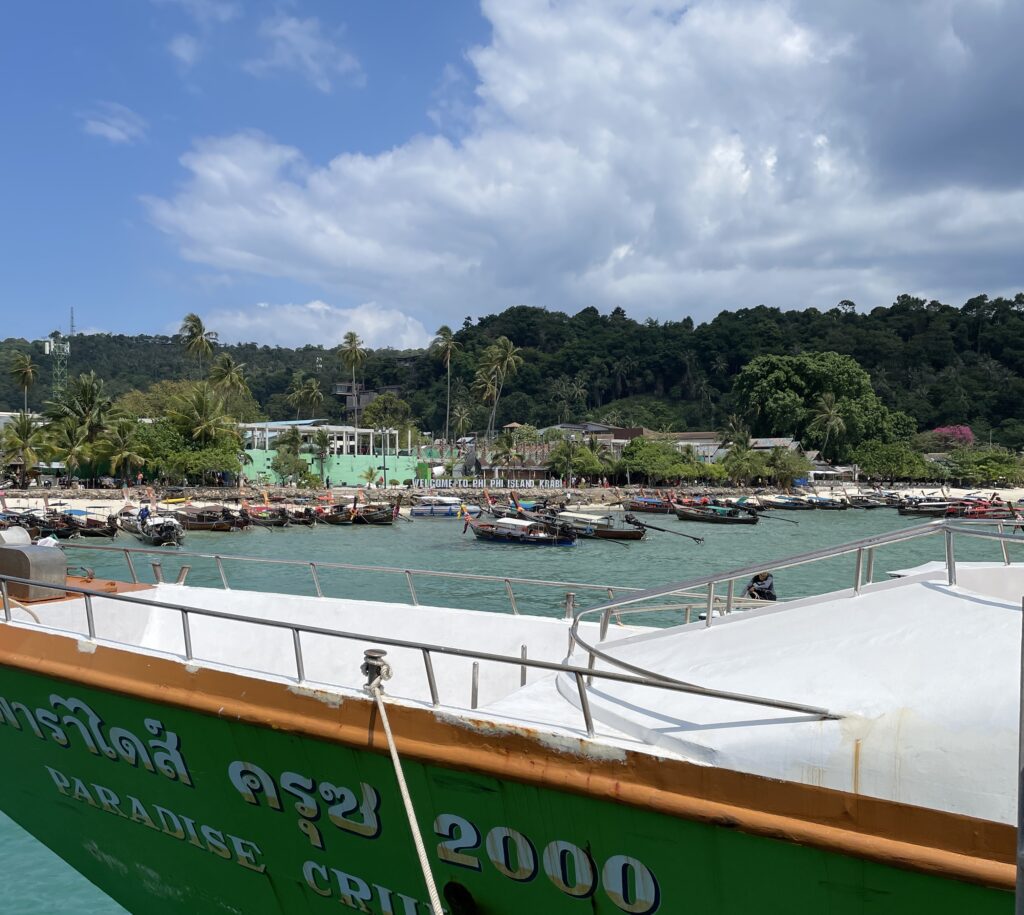 ferry arriving in Koh Phi Phi, many longtail boats and limestones in the distance / Krabi Airport to Koh Phi Phi
