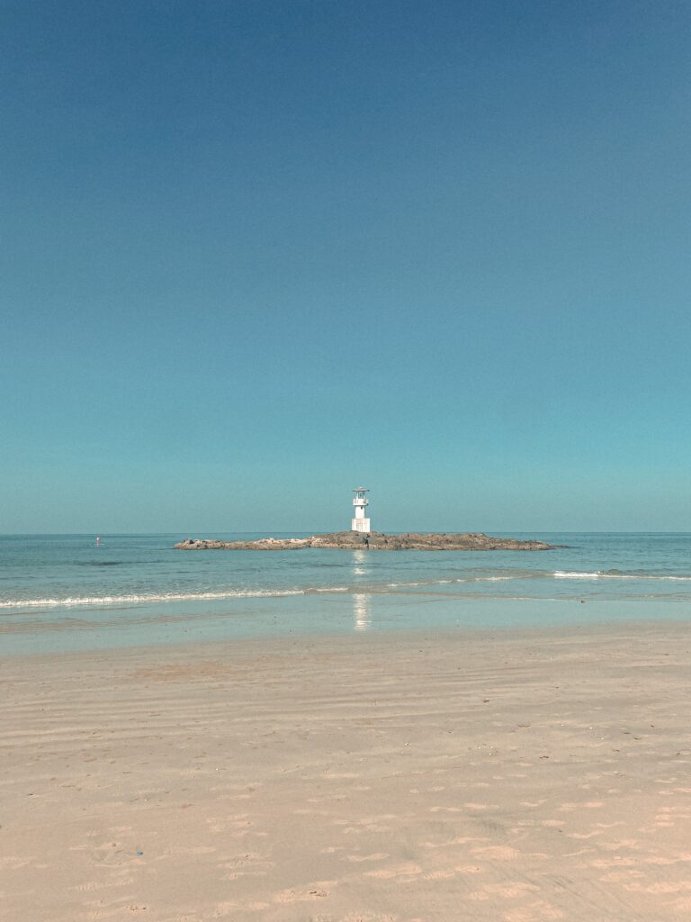 beautiful crystal clear shoreline in Khao Lak with a small lighthouse in the distance