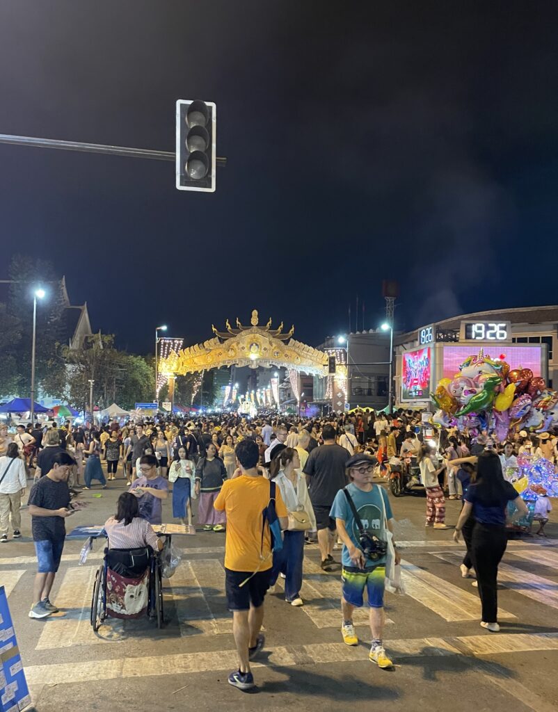 several locals and tourist walking amongst the night market and closed streets for Yi Peng Festival near Nawarat Bridge in Chiang Mai