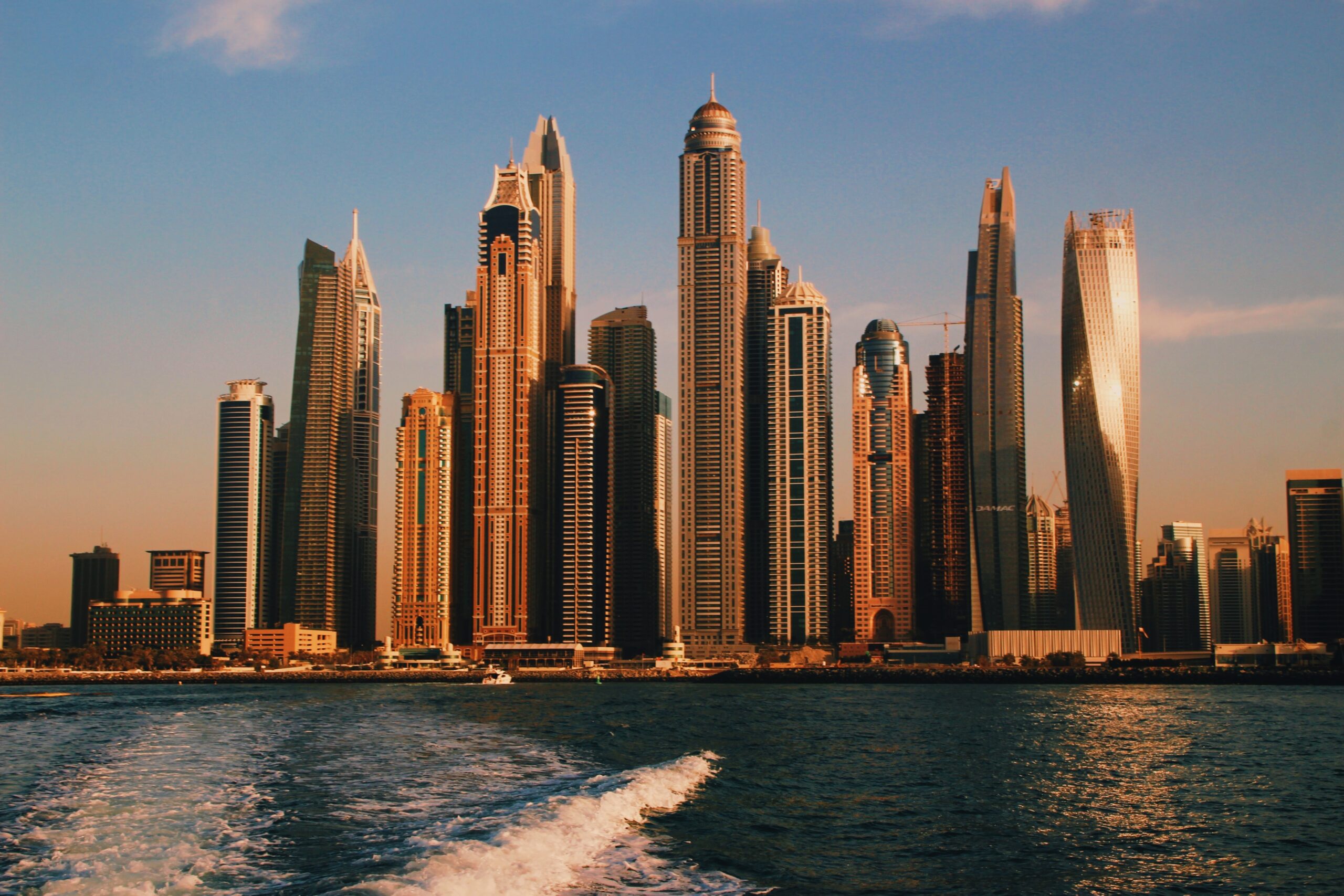 Dubai's remarkable skyscrapers shown from a boat during sunset / places like Dubai