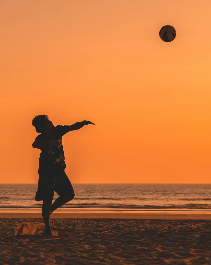a man waiting for a volleyball during a vibrant orange sunset on the beach in Khao Lak, Thailand