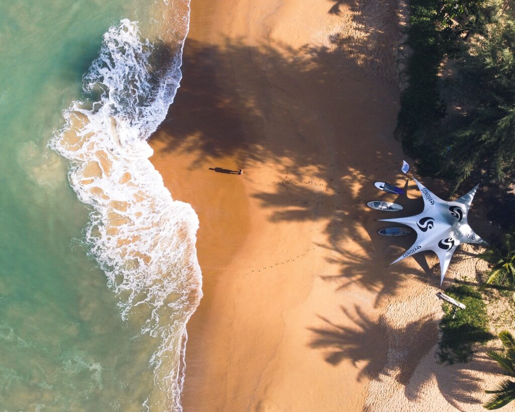 an aerial photo of a secluded empty beach with only a few surfboards in Khao Lak, Thailand
