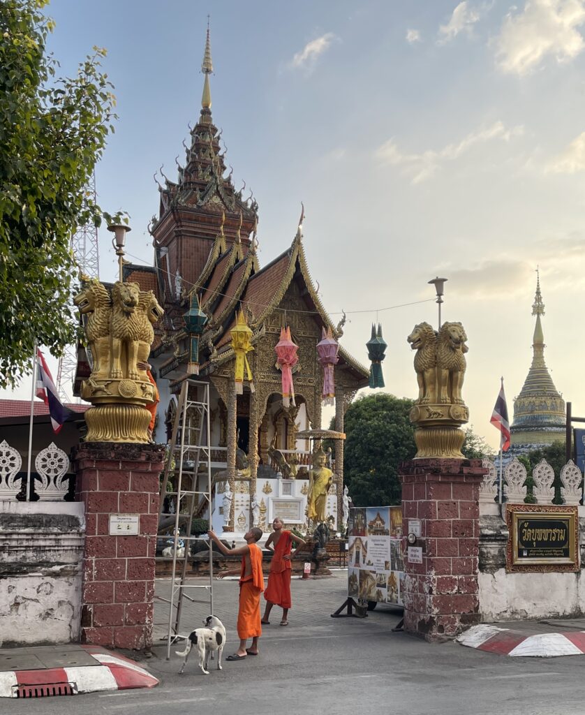 three monks standing outside a famous temple in the evening in Chiang Mai