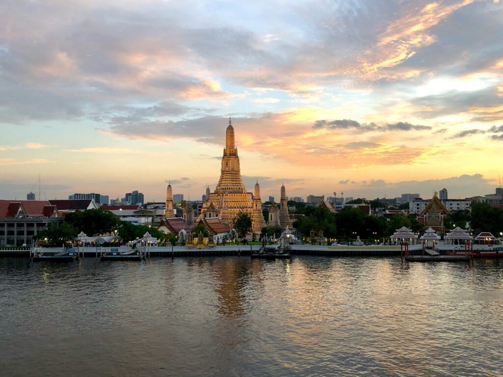 vibrant cotton candy skies around a gold temple by the river in Bangkok, Thailand