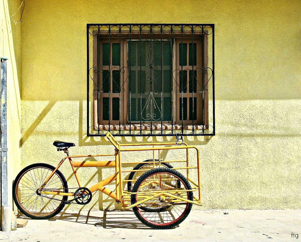 a yellow tricycle bike parked by a yellow house in Isla Mujeres  