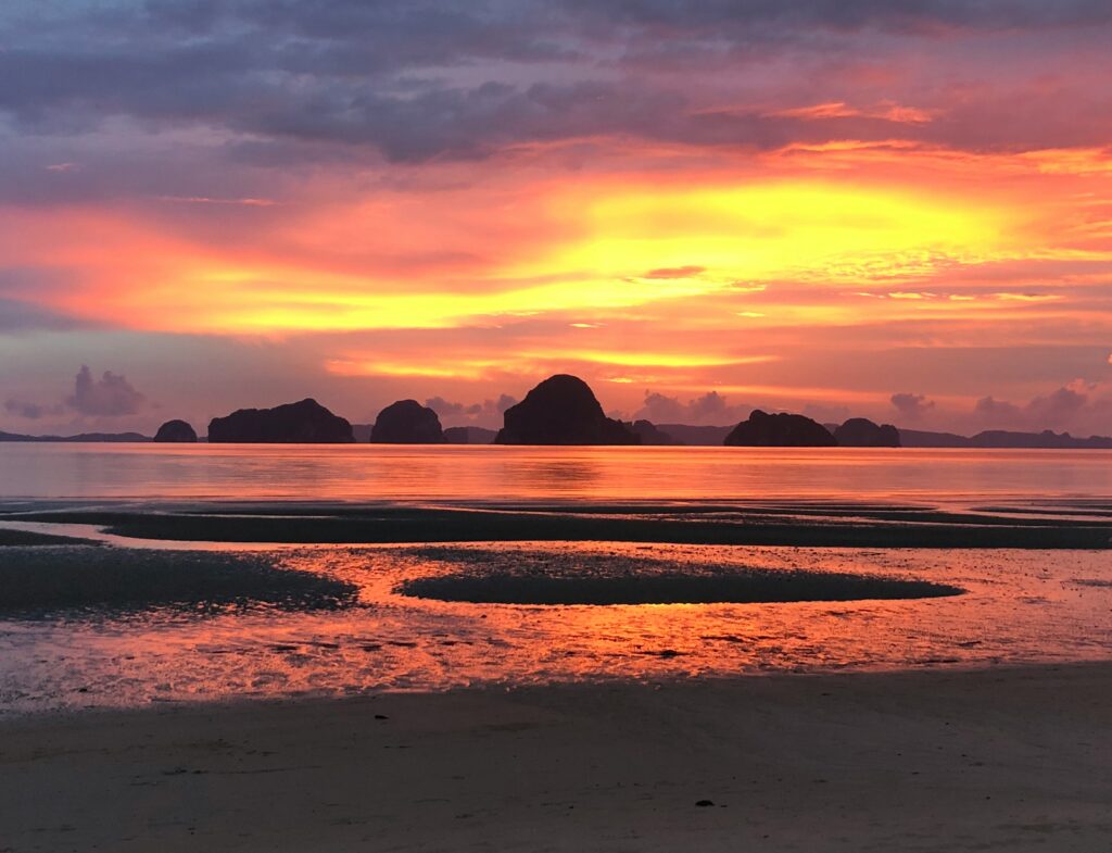 a vibrant orange and yellow sunset at the beach in Tubaek Krabi